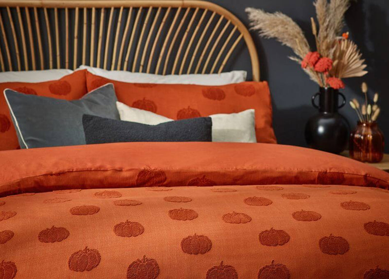 Three Halloween cushions with abstract, witchy printed designs, arranged on a blue sofa with a white throw.