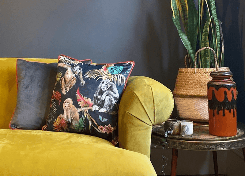 A living room with a brown leather and grey fabric sofa, both decorated with colourful geometric and frilled cushions.