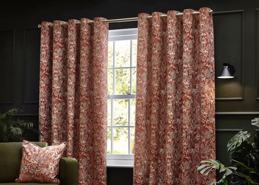 A pair of sage green curtains with a contemporary design of Bengal tigers and jungle foliage, hung in front of an olive green wall in a decorated living room. 