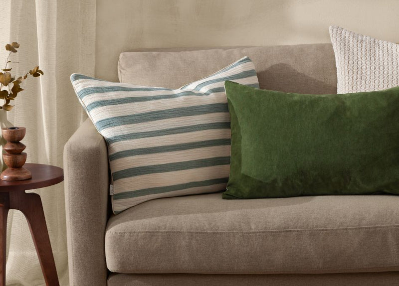 beige sofa, with stripey navy cushion, green cushion and cream cushion, emphasising slow decorating