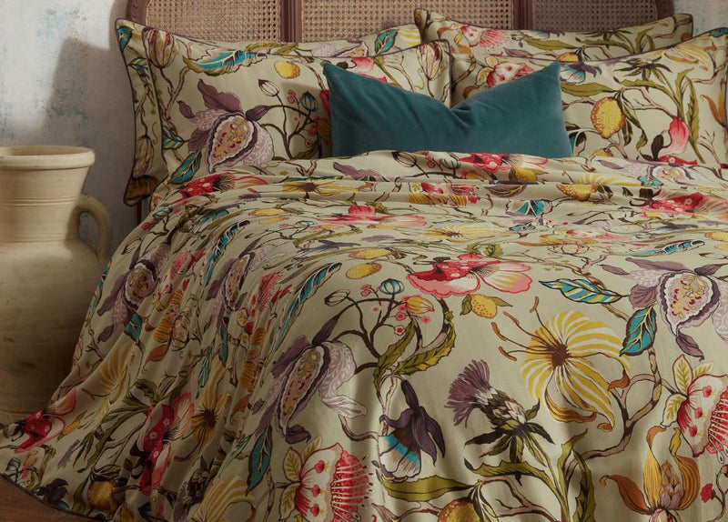 A biophilic bedroom design with neutral cotton muslin bedding, earthy beige and green scatter cushions, a moss bedspread, a white mohair throw and indoor plants.