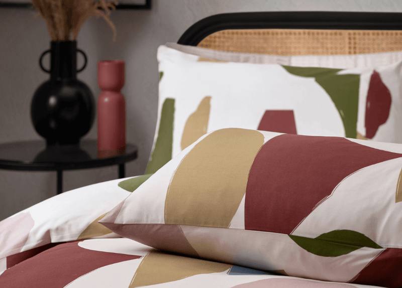 scandi style bed decor with neutral cushions and olive green throw on bed