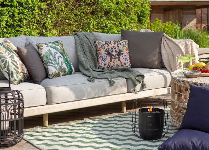 An outdoor entertaining area decorated with a garden sofa, outdoor cushions and an abstract outdoor rug.