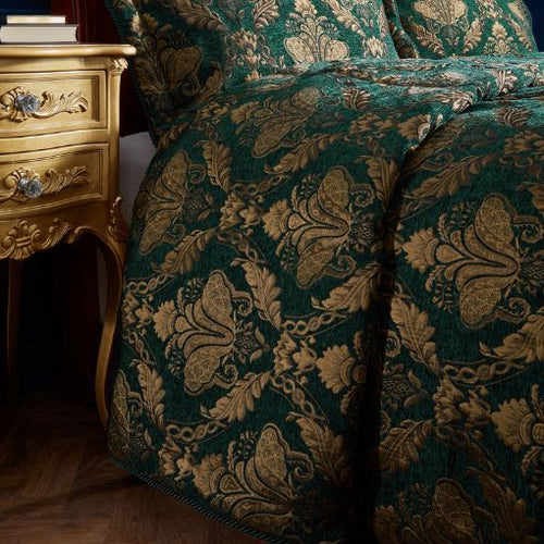 A closeup image of an emerald green jacquard bedspread with a gold damask pattern.
