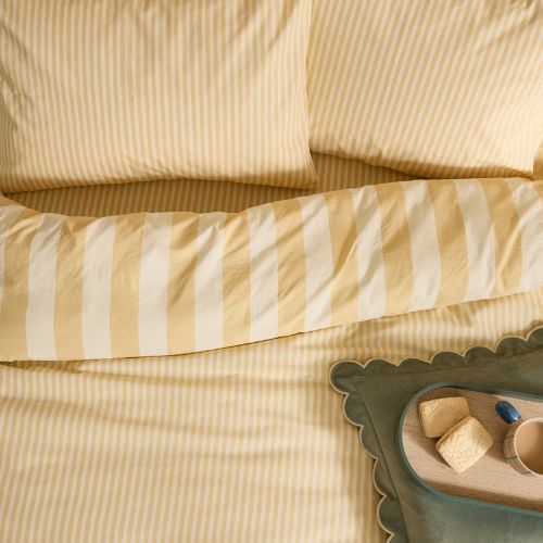 A yellow bedding set with scalloped yellow and white stripes with a ruffled edge finsh with matching pillowcases