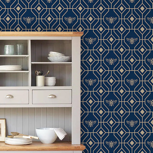 Kitchen wallpaper with a geometric bee and honeycomb design in navy and gold hues, hung in a kitchen behind a storage cabinet.