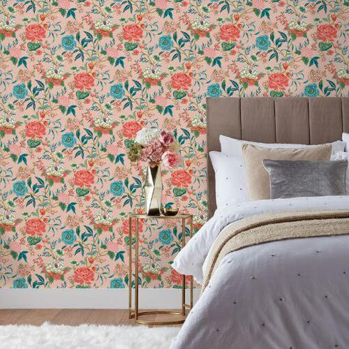 Floral wallpaper with a pink, red and blue design of bright garden azalea blooms, hung in a bedroom.