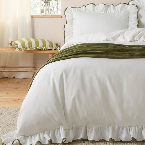 Plain white bedding set with olive green piped edge ruffles, a cotton khaki green throw over the top
