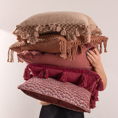 A person holding a selection of Valentine's-inspired cushions in a range of pink and red shades.