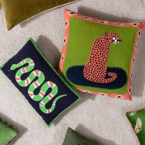 Animal cushions with embroidered designs of snakes and cheetahs in vibrant exotic hues.